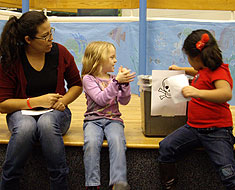 Kids recycling paper and teacher watching