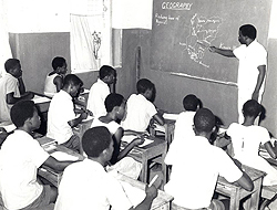 Andrew Foster, standing at the chalkboard in a classroom. His students are sitting at their desks.