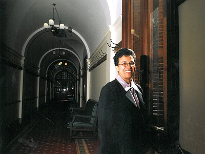 The halls of the parliament, Wilma Newhoudt-Druchen stands in front of a doorway, presumably leading to her office.