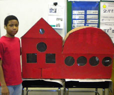 Image: A KDES student with red model building in a classroom