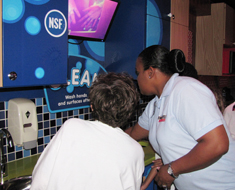 Image: USDA staffer shows germs on the hands of a student volunteer before demonstrating proper handwashing.