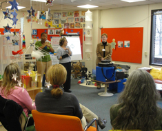 Image: Sandra Newcomb (on right, in brown jacket) from Connections of Beyond Sight and Sound leads a workshop for PIP and Clerc Center support staff.