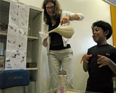 Image: Samuel Bachoo describes his water wheel works while teacher’s aide Renee Poyer assists.