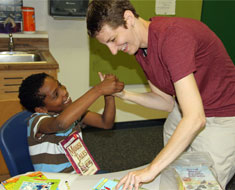 Image: Too hard to choose! Amo Konkel-Harmon tries to get teacher Melissa Shumate to raise two fingers for two books. (Photo: Susan Flanigan)