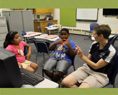 Image: On the last day of ESY, Crystal Velasquez and Deonate Bates chat with teacher Melissa Shumate about the medals they won in the ESY Olympic Games. (Photo: Susan Flanigan)