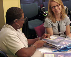 Image: A volunteer trainer works with a mother at a SRP family session hosted by Hearing Me at The Howard Phillips Center for Children & Families, part of the Arnold Palmer Hospital for Children in Orlando, Florida. The families use the Clerc Center-developed SRP book bags as instructional materials for how to read to their children using ASL. (All photos courtesy of Tanya Williams)