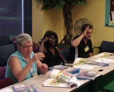 Image: Family members practice signs for a story while the children meet in a separate room to enjoy story-related activities.