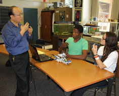 Image: Teacher Mark Tao and students Daimere Phillips and Margaret Hangstorfer discuss how to solve a technical problem with their robot.