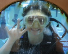 Image: MSSD student Mary Ann Gardner signs “I love you” while inside the dive chamber. The underwater chamber simulates the effect of moving in space for repair work. Sign language made access to communication much easier during the scuba exercises.