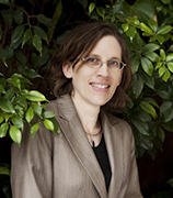 Dr. Linda Campbell, wearing a tan suit, black blouse and sitting among green plants