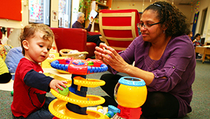 Certificate Programs Woman and todder engaging in an educational play setting.