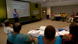 Customized Training Programs A group watching a presenter giving a presentation with a projector.