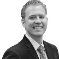 A black and white photo of Thomas Horejes wearing a suit and tie.