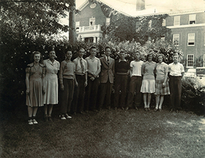 Bernard Bragg's class at American Scool for the Deaf in 1943. They are standing outside in front of a building, on a grassy area with trees and bushes behind them.