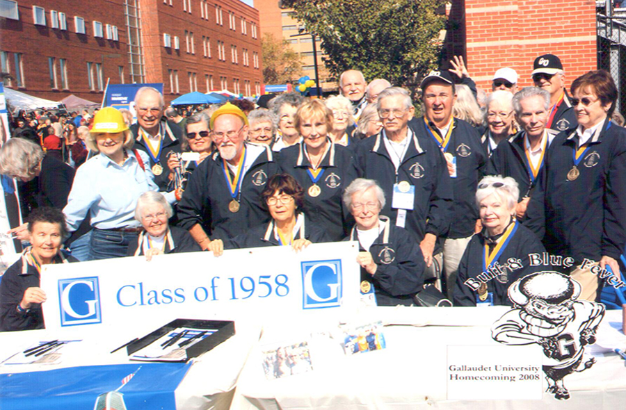 Large group photo of Class of 1958 with Dr. Jane Norman with their Class of 1958 Banner - all are standing together outside during Homecoming.