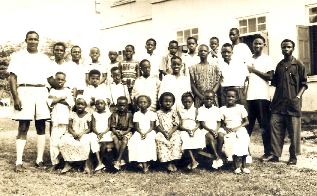 Foster posing with about 30 pupils all wearing white outfit.
